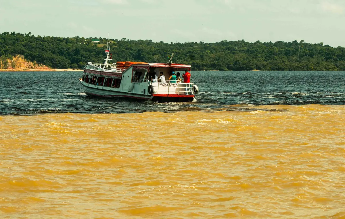 A boat at the line where dark and light water meet near Manaus